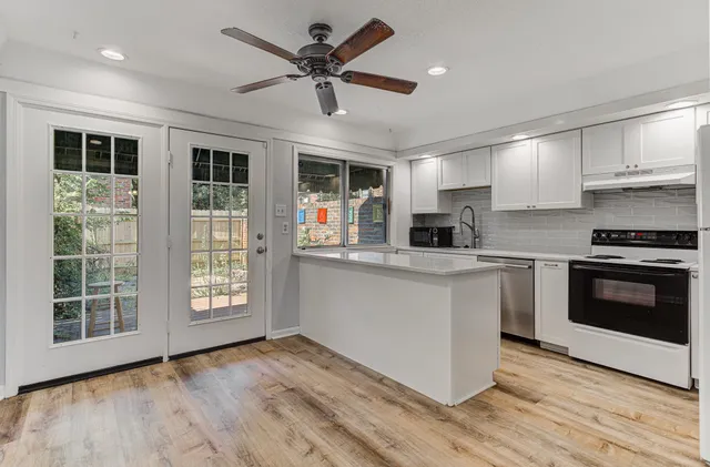 a kitchen with granite countertop a stove a sink dishwasher a refrigerator and a microwave oven with wooden floor