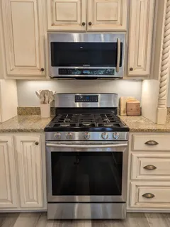 a large kitchen with a dining table wooden floor stainless steel appliances and living room view