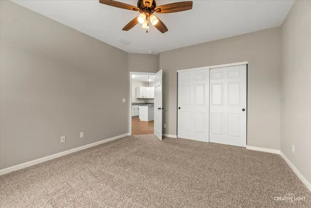 a view of an empty room and chandelier fan