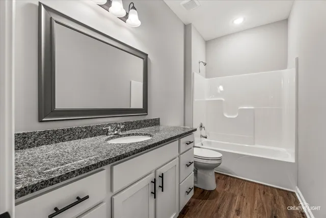 a bathroom with a granite countertop sink a toilet and a mirror