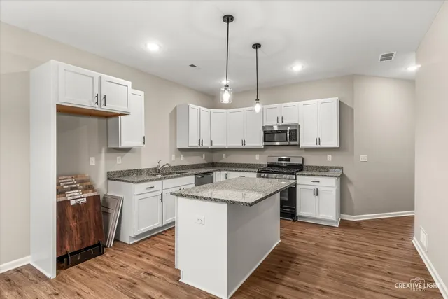 a kitchen with stainless steel appliances granite countertop a stove a sink and a refrigerator