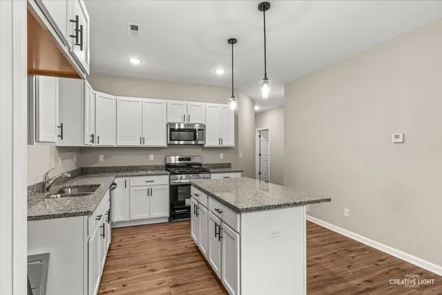 a kitchen with stainless steel appliances granite countertop a stove a sink and a refrigerator