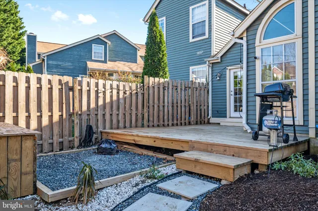 a backyard of a house with wooden floor chairs and wooden fence