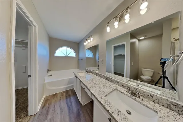 a bathroom with a granite countertop tub a double vanity sink and a large mirror