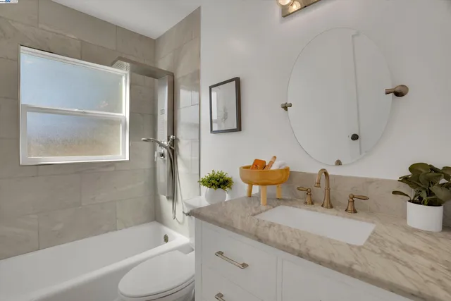 a bathroom with a granite countertop sink mirror toilet and bathtub