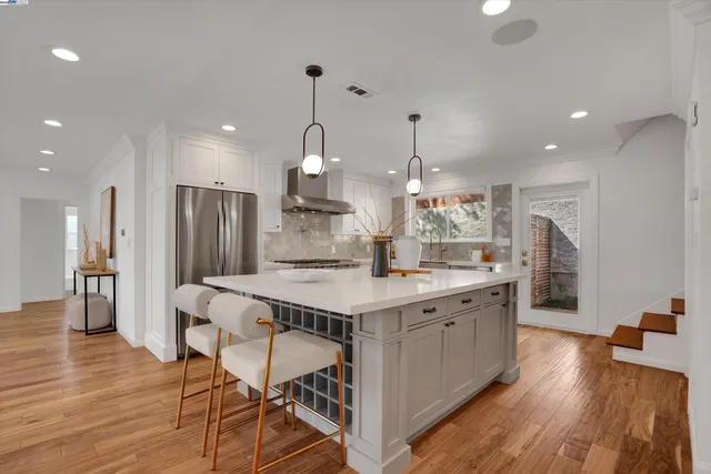 a kitchen with stainless steel appliances kitchen island granite countertop a table chairs sink and wooden floor