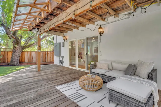 a view of a patio with couches and a table and chairs with wooden floor and fence