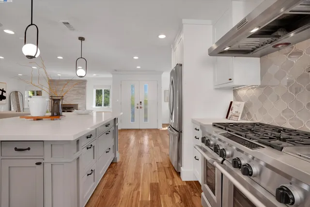 a kitchen that has a lot of stainless steel appliances and wooden floor