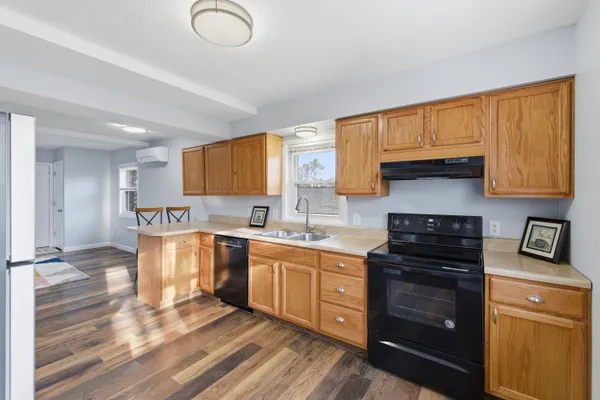 a kitchen with stainless steel appliances granite countertop a refrigerator a sink a stove and white cabinets with wooden floor