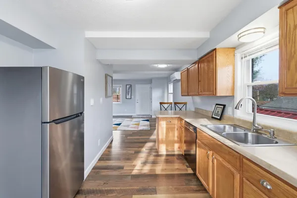 a kitchen with stainless steel appliances granite countertop a refrigerator a stove and a sink with large window