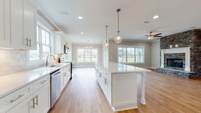 a large kitchen with a large counter top a sink stainless steel appliances and cabinets