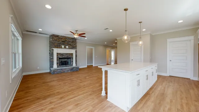 a large kitchen with kitchen island a stove a sink dishwasher and a fireplace with wooden floor