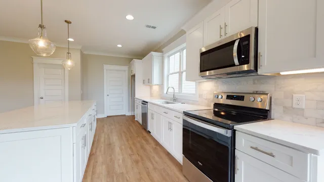 a kitchen with stainless steel appliances granite countertop a stove a sink and a microwave