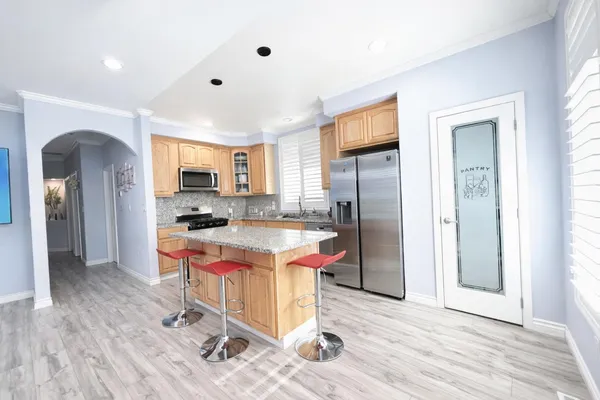 a kitchen with stainless steel appliances granite countertop a refrigerator a stove top oven and a sink with cabinets
