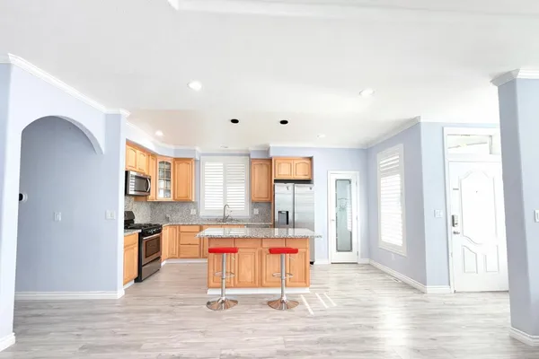 a room with stainless steel appliances kitchen island granite countertop a refrigerator and a sink