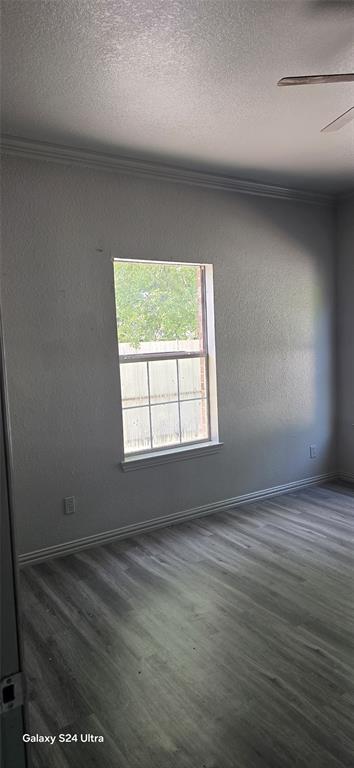 609 Elwayne Avenue Dallas, TX 75217 - Photo 6 of 9 Room featuring wood-finish flooring, a window with exterior tree scenery, white baseboards, and crown molding