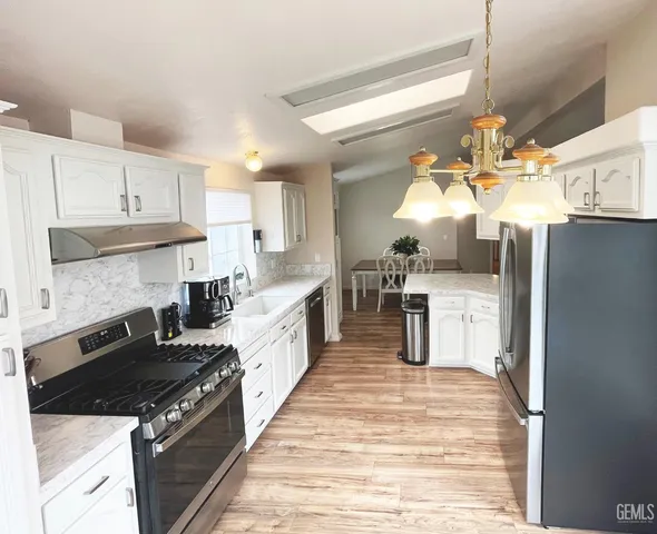 a kitchen with granite countertop a sink stove and refrigerator