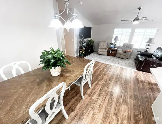 a dining room with wooden floor a chandelier a wooden table and chairs