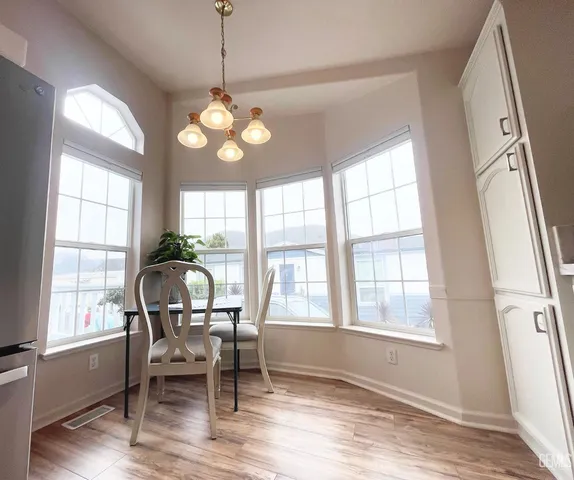 a kitchen with granite countertop a refrigerator a sink dishwasher stove and white countertops with wooden floor