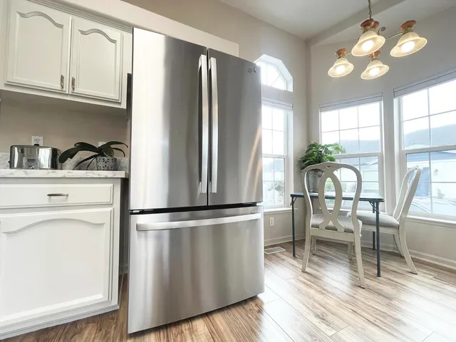 a large kitchen with kitchen island a stove a sink dishwasher and white cabinets with wooden floor