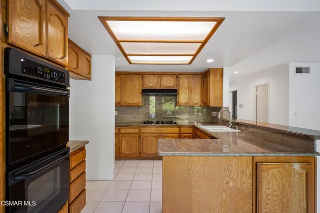 a kitchen with stainless steel appliances granite countertop a stove a sink and a microwave