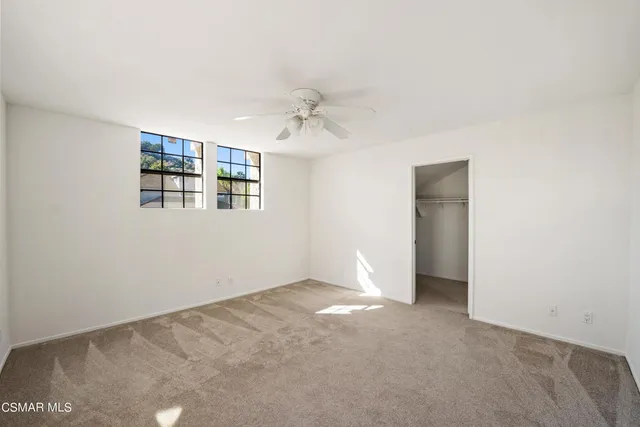 an empty room with windows and ceiling fan