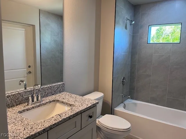a bathroom with a granite countertop sink toilet mirror and bathtub