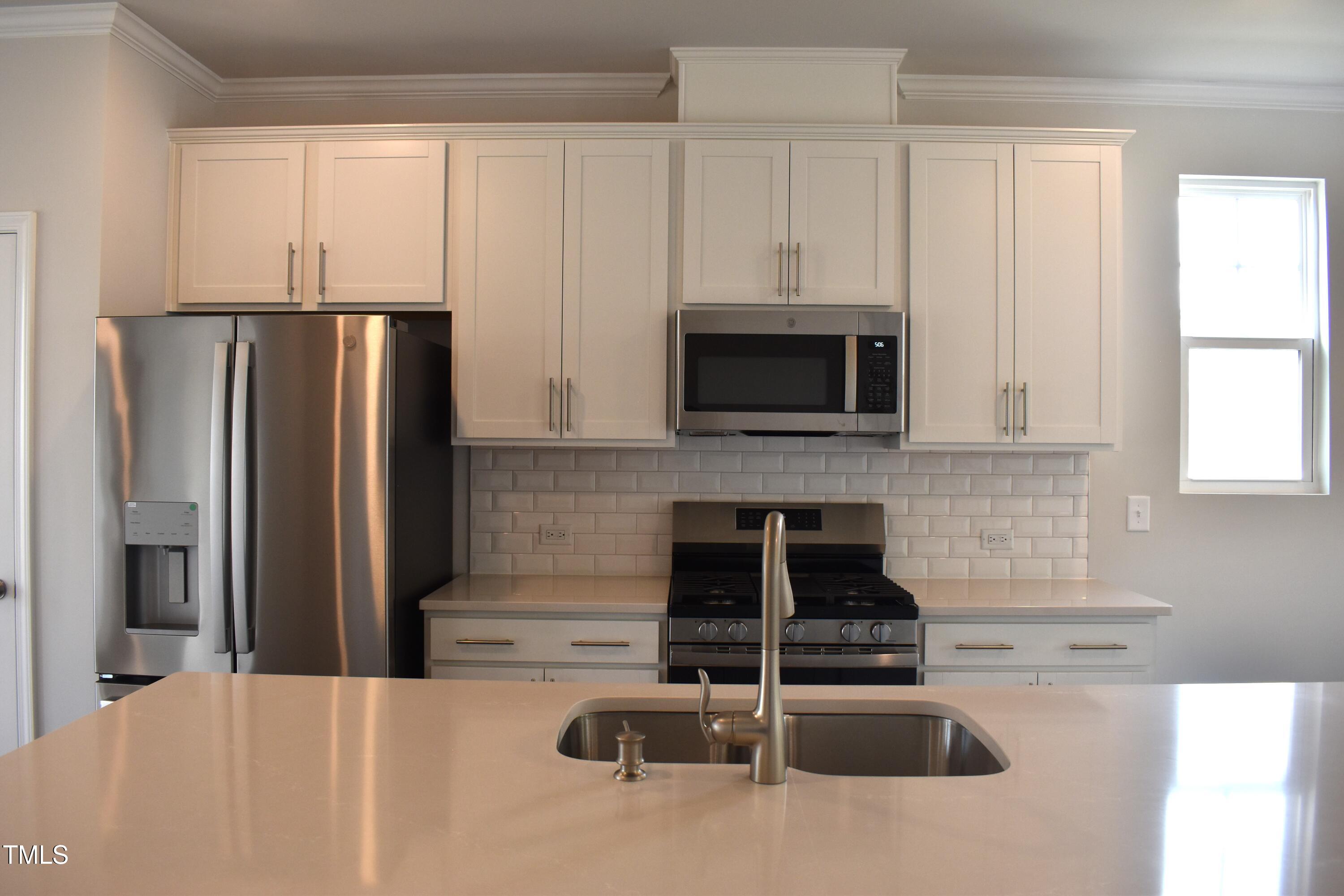 301 Deercroft Drive Apex, NC 27539 - Photo 14 of 33 a kitchen with granite countertop a refrigerator stove and microwave