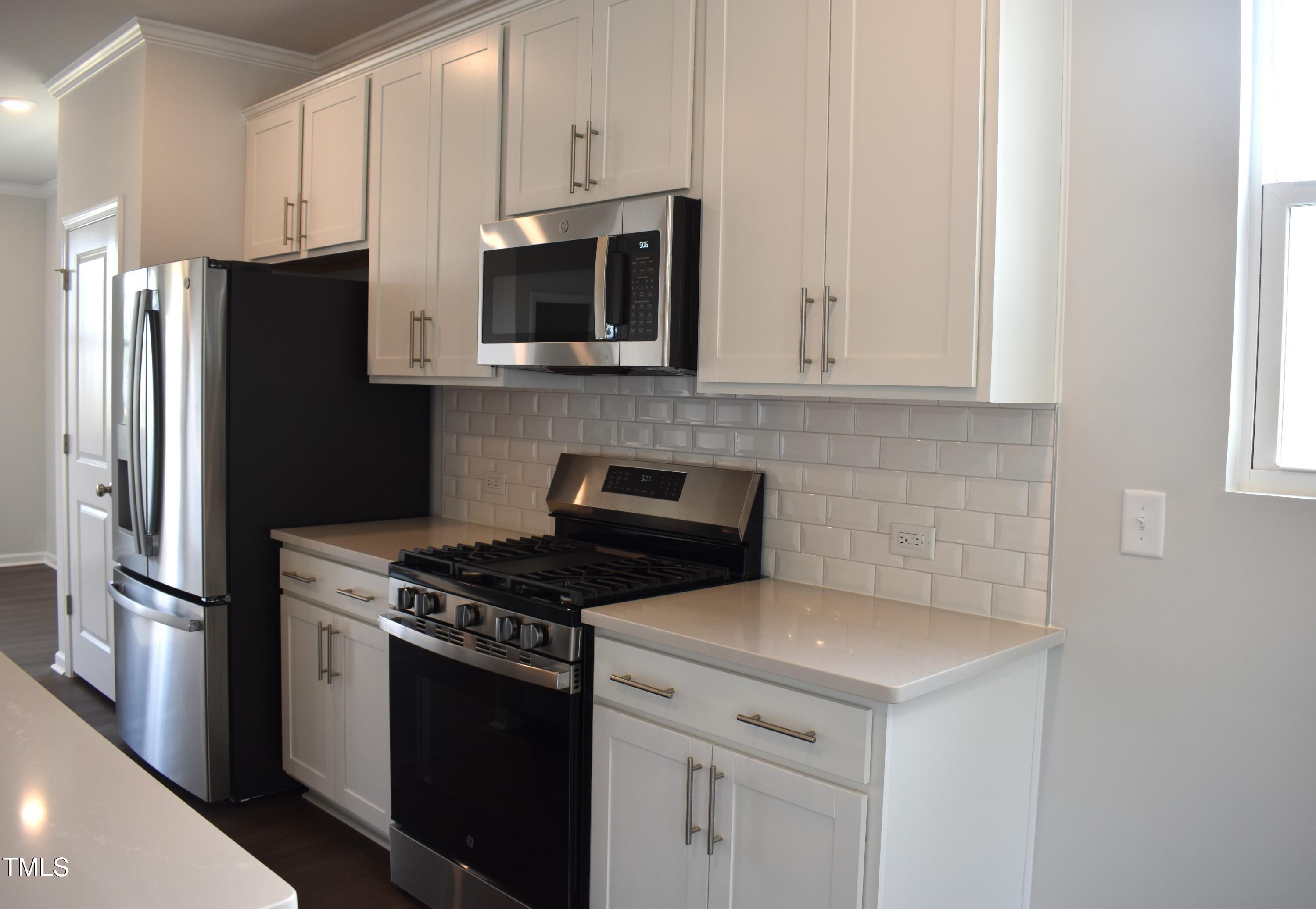 301 Deercroft Drive Apex, NC 27539 - Photo 15 of 33 a kitchen with stainless steel appliances a stove a microwave and a refrigerator