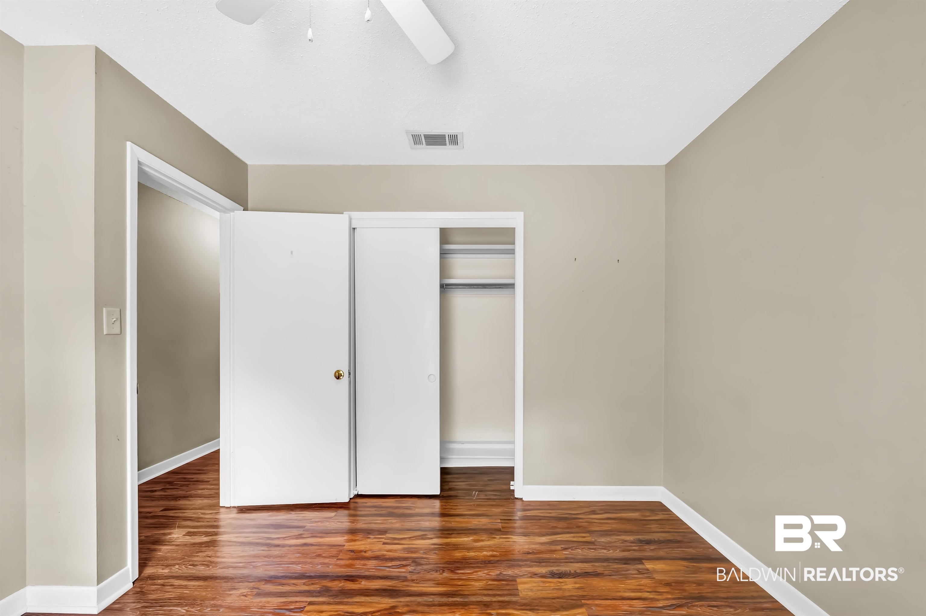 28 Caisson Trace Spanish Fort, AL 36527 - Photo 39 of 51 Unfurnished bedroom featuring visible vents, ceiling fan, baseboards, a closet, and wood finished floors