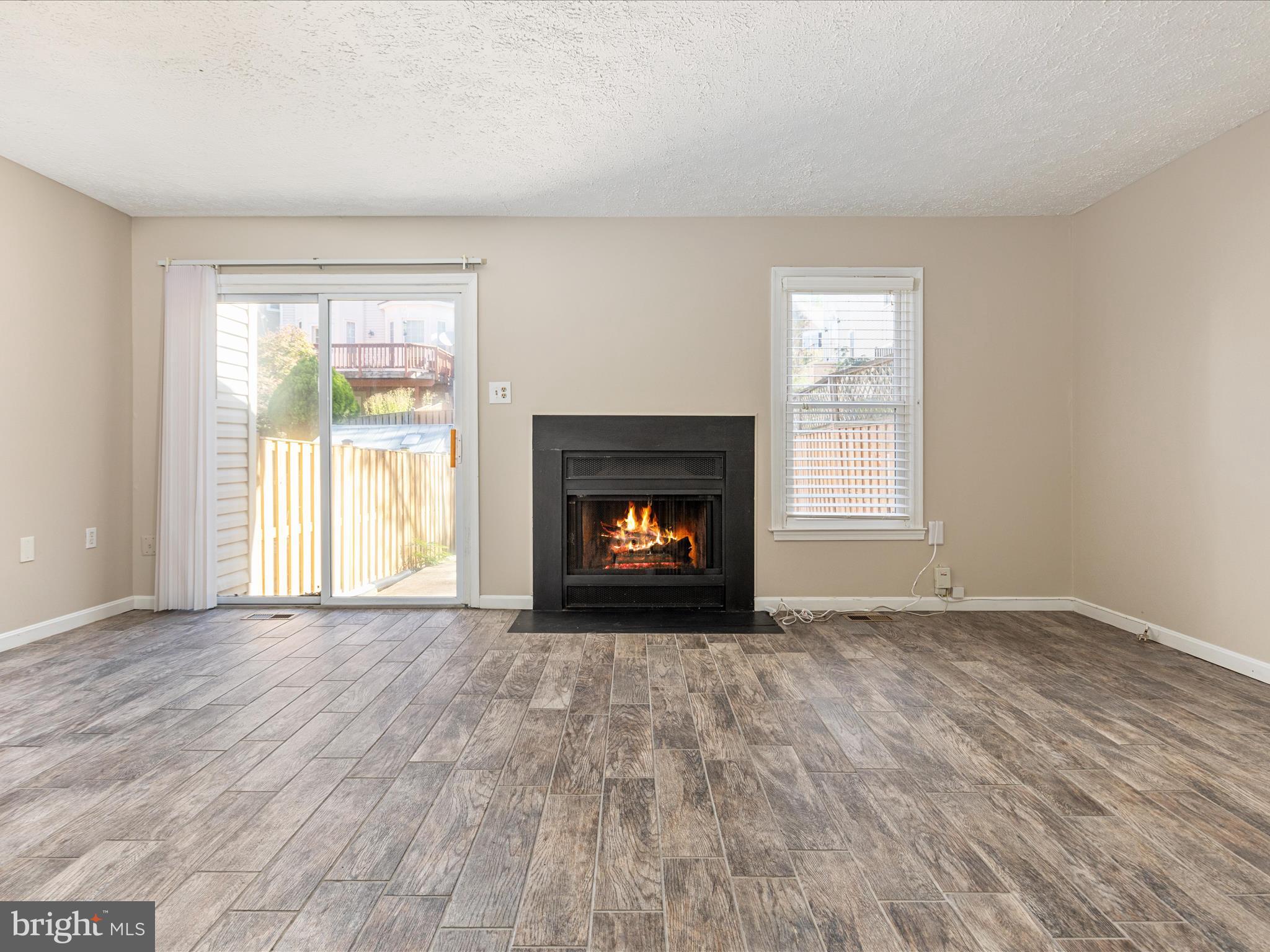 7219 Kousa Lane Springfield, VA 22152 - Photo 9 of 34 an empty room with wooden floor fireplace and windows