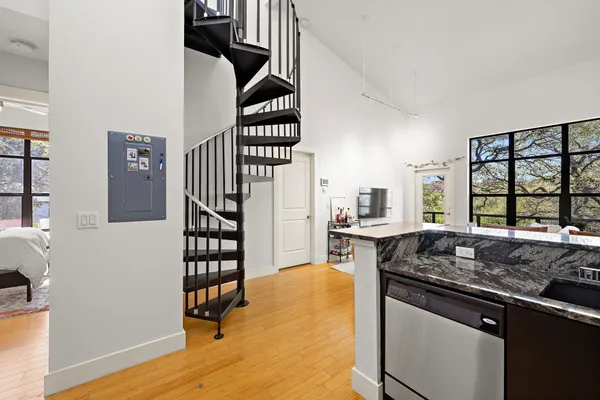 a kitchen with stainless steel appliances granite countertop a stove top oven a sink dishwasher a dining table and chairs with wooden floor
