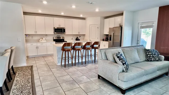 a living room with furniture a dining table and a refrigerator