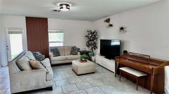 a living room with furniture and a refrigerator