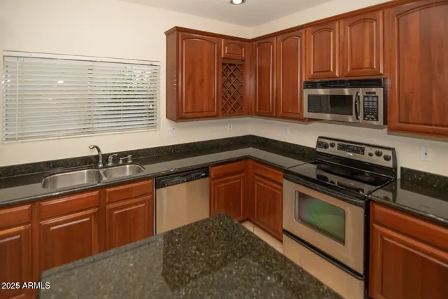 a kitchen with granite countertop wooden cabinets stainless steel appliances and a sink