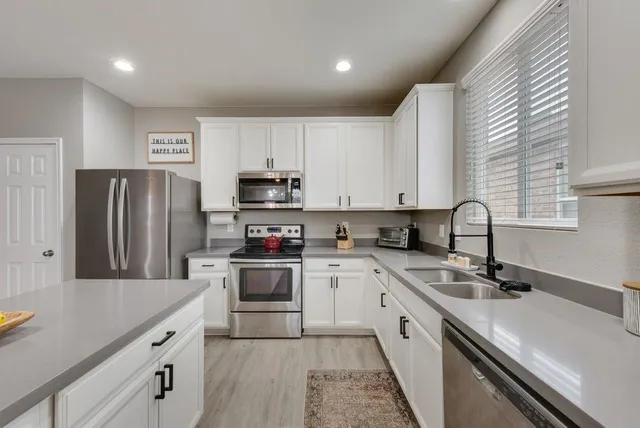 a kitchen with appliances a sink a counter top space and cabinets