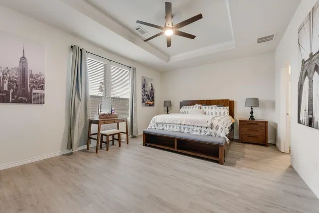 a living room with chairs a chandelier and a dining table with wooden floor