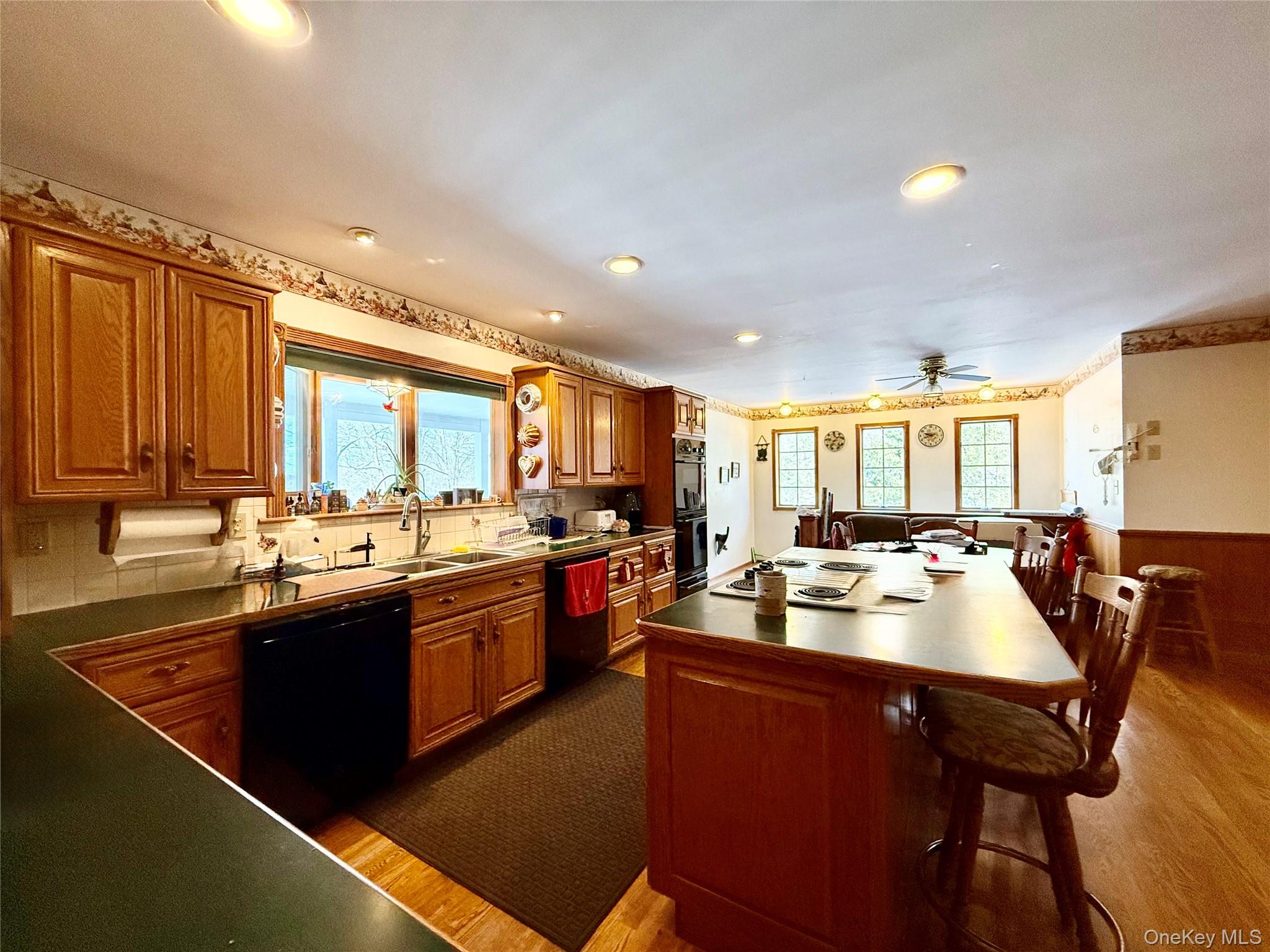 912-918 Hollow Road Salt Point, NY 12578 - Photo 5 of 35 Kitchen with oak cabinets, wood flooring, a breakfast bar area, black appliances, and tasteful backsplash