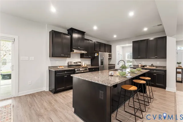 a kitchen with stainless steel appliances granite countertop a stove refrigerator and a sink