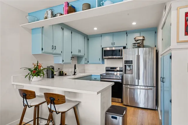 a kitchen with stainless steel appliances a refrigerator a stove a sink cabinets and a dining table