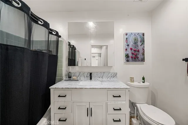 a bathroom with a granite countertop sink mirror vanity and toilet