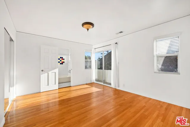 a view of an empty room with window and wooden floor