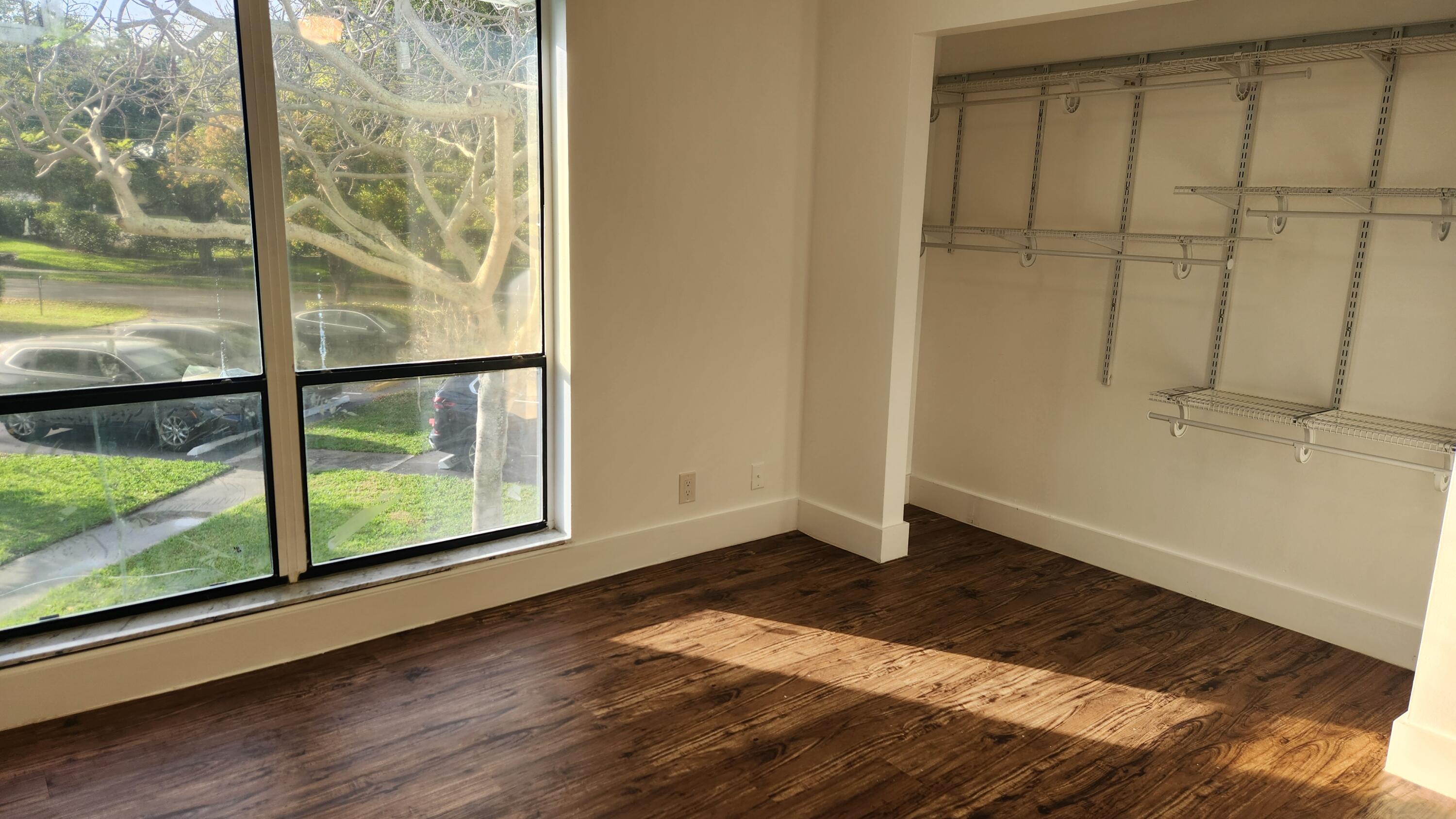 517 Dotterel Road, Unit 31C Delray Beach, FL 33444 - Photo 24 of 31 a view of an empty room with wooden floor and a window