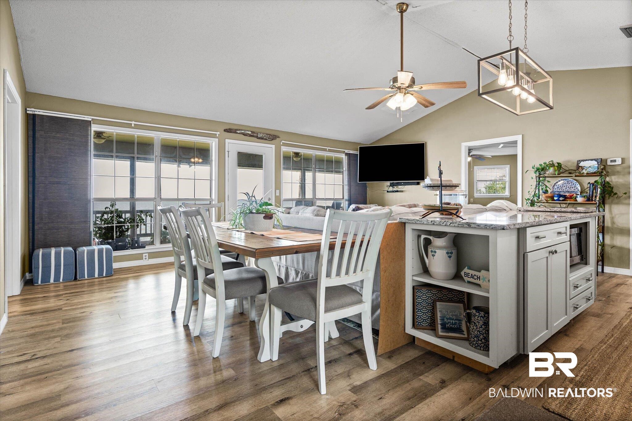 9100 Shell Belt Road Coden, AL 36523 - Photo 3 of 38 Open-concept living space featuring wood-finish flooring, a vaulted ceiling, and an integrated kitchen island with a light-colored countertop