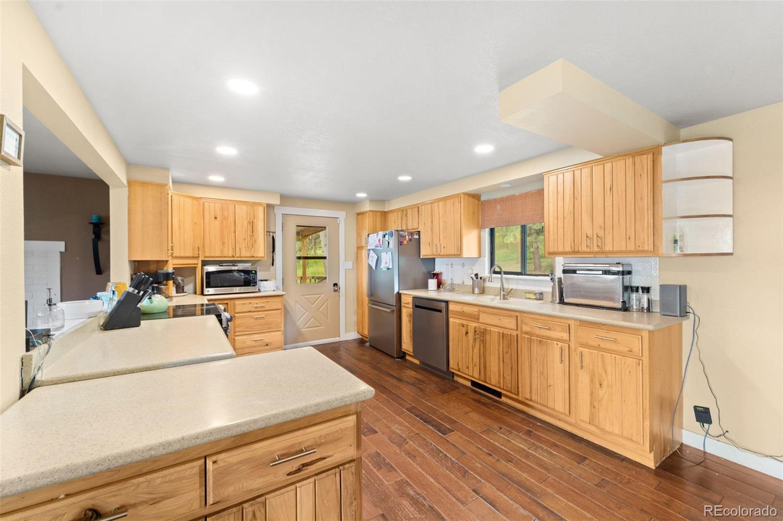 10829 Bartlett Trail Rye, CO 81069 - Photo 8 of 40 a kitchen with stainless steel appliances kitchen island granite countertop a stove a sink a refrigerator and white cabinets with wooden floor