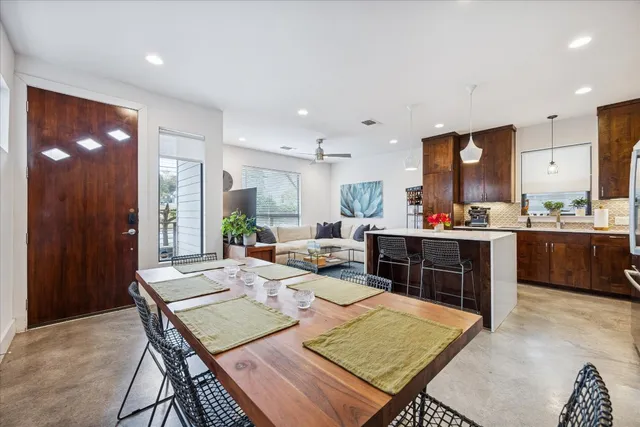 a kitchen with stainless steel appliances kitchen island granite countertop a refrigerator a sink a stove and chairs with wooden floor