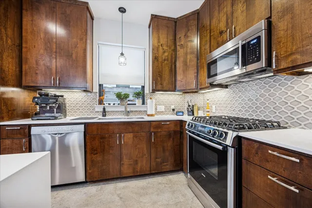a kitchen with stainless steel appliances granite countertop a stove a sink and a microwave