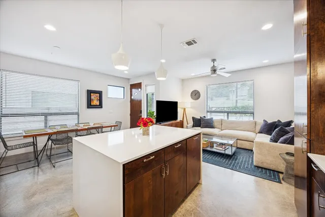 a large living room with stainless steel appliances kitchen island a large window in it