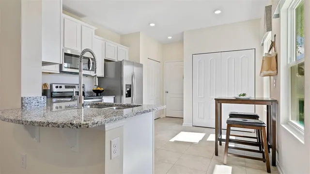 a kitchen with stainless steel appliances granite countertop a refrigerator a stove and a sink