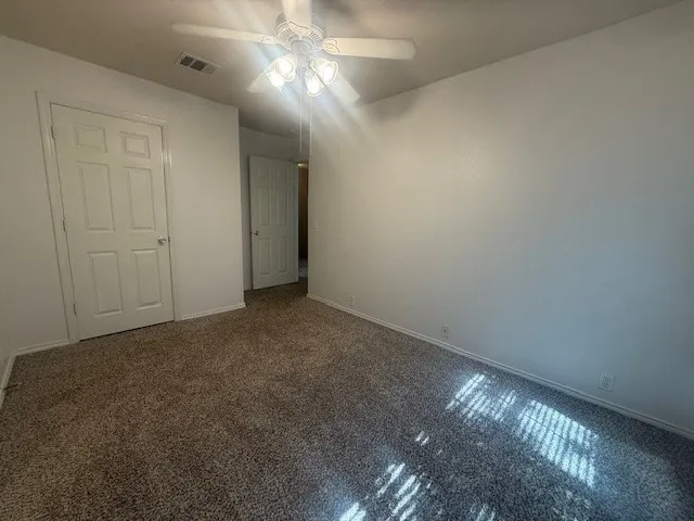 an empty room with a fan & a window